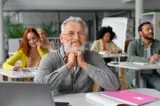 Man lacht naar de camera in een klaslokaal.